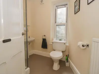 a bathroom with a toilet and a sink and a window at 5 Tai Isa in Barmouth