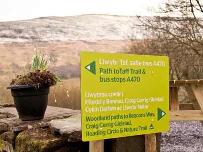 a yellow sign sitting on a wall with a plant at YHA Brecon Beacons in Brecon