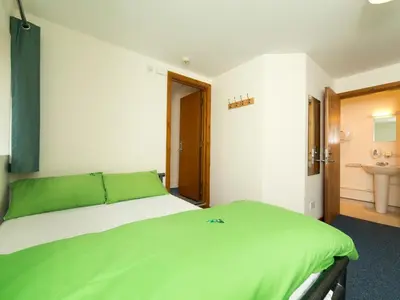 a bedroom with a large bed with green sheets at YHA Brecon Beacons in Brecon