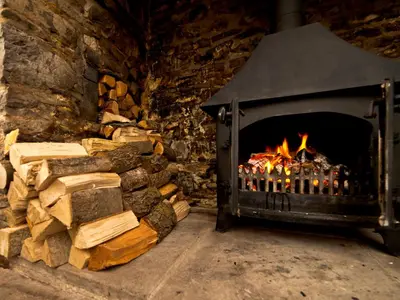 a stone fireplace with a pile of fire wood at YHA Brecon Beacons in Brecon