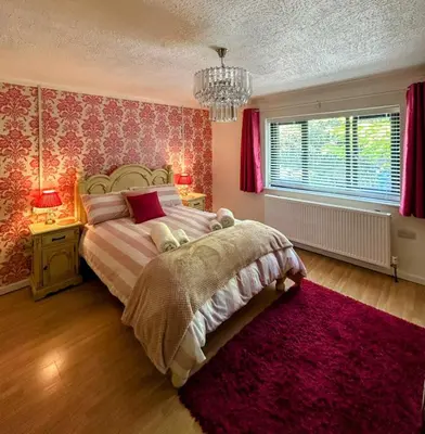 a bedroom with a bed and a red wall at Bryn Mynach Guest House in Barmouth