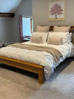 a large bed with a wooden frame in a bedroom at The Cottage at Sychnant Farm in Talgarth