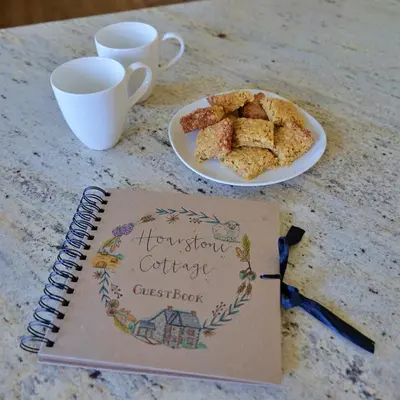 a notebook next to a plate of cookies on a table at Country Cottage with Far Reaching Views in Presteigne