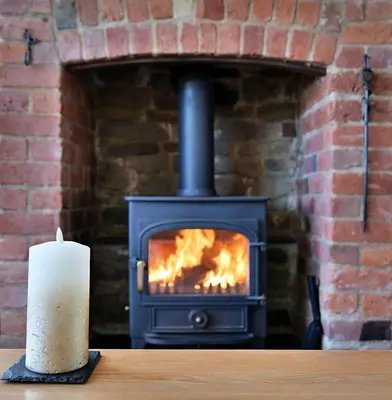 a fireplace with a candle next to a table with a candle at Country Cottage with Far Reaching Views in Presteigne