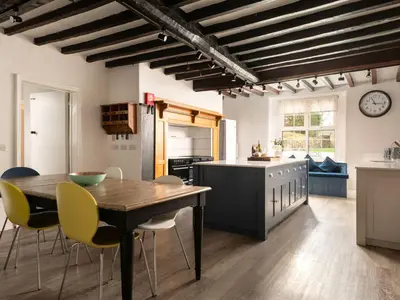 a kitchen with a wooden table and yellow chairs at Fron Dderw in Bala