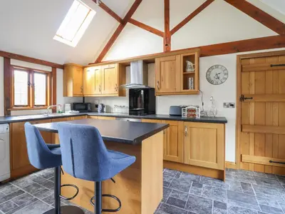 a kitchen with wooden cabinets and a counter top at Ysgubor Fachwen in Newtown