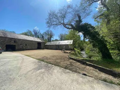 a large barn with a large tree next to a driveway at Crymlyn barn in Llanwrda