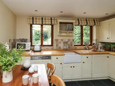 a kitchen with white cabinets and a table with chairs at Nant Glas in Llanwrda