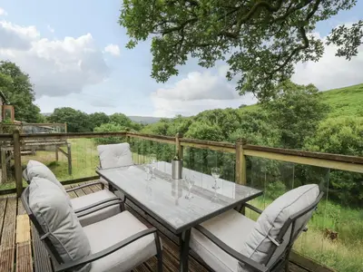 a table and chairs on a deck with a view at Nant Glas in Llanwrda
