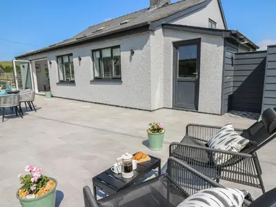 a patio with chairs and a table and a house at Rhiwmynach in Aberystwyth
