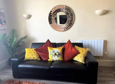 a black leather couch with colorful pillows in a living room at Sunny View in Aberystwyth