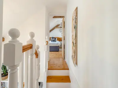 a hallway with white walls and a staircase with a bed at Y Beudy in Capel Bangor