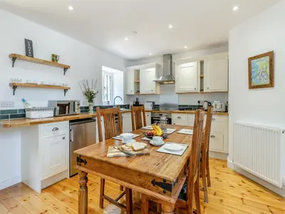 a kitchen with a wooden table and chairs at Y Beudy in Capel Bangor