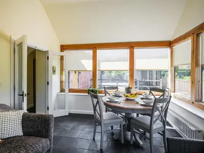 a dining room with a table and chairs and windows at Orchard View in Minsterley