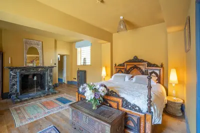 a bedroom with a large bed and a fireplace at Llanerchydol Hall Suites in Welshpool