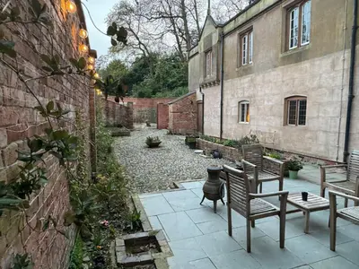 a patio with two chairs and a table next to a building at Llanerchydol Hall Suites in Welshpool