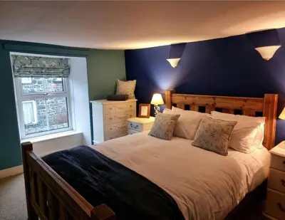 a bedroom with a large bed with a blue wall at Glasfor Cottage in Llwyngwril