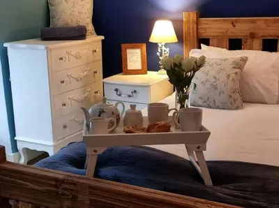 a bedroom with a bed with a table with flowers at Glasfor Cottage in Llwyngwril