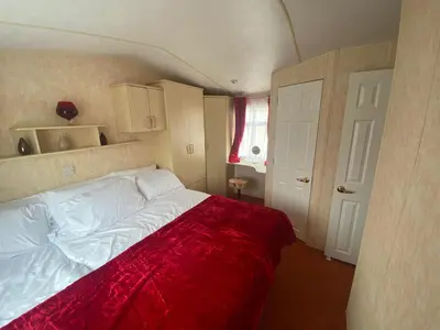 a bedroom with a large bed with a red blanket at 98Lemmington by the beach Ynyslas, Borth in Borth