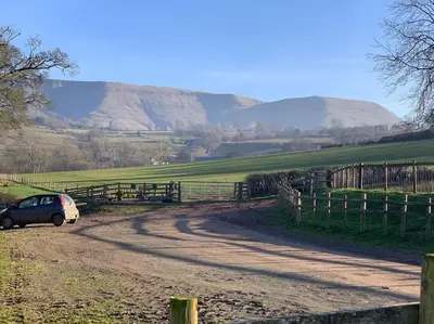a car parked on a dirt road with mountains in the background at Cottage with outstanding views in Velindre