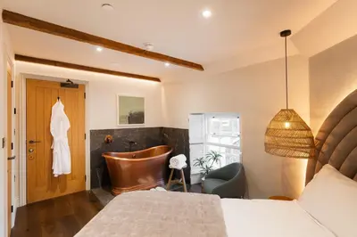 a bedroom with a bed and a chair and a tub at Hive Townhouse in Aberaeron
