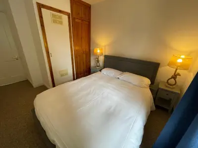 a bedroom with a large white bed with two lamps at Glanywerydd Cottage in Barmouth