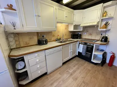 a kitchen with white cabinets and a sink and a stove at Glanywerydd Cottage in Barmouth