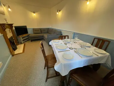 a dining room with a table and a couch at Glanywerydd Cottage in Barmouth