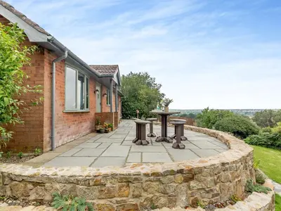 a patio with two tables in front of a house at High Bank in Pontesbury