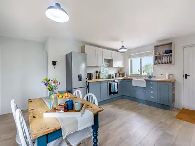 a kitchen and dining room with blue cabinets and a wooden table at High Bank in Pontesbury