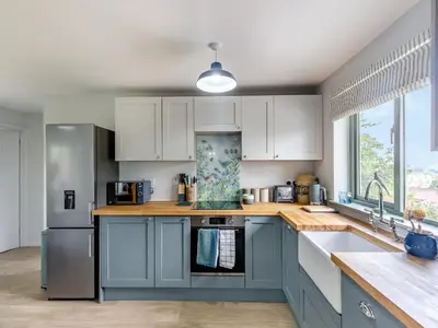 a kitchen with blue cabinets and a sink at High Bank in Pontesbury