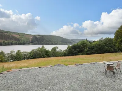 a table and chairs sitting on top of a gravel road near a lake at Hen Blaid in Oswestry