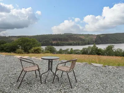 a table and two chairs sitting next to a lake at Old Cart House in Oswestry