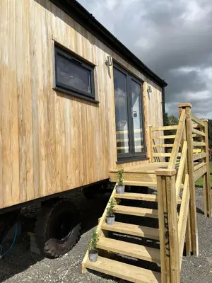 a wooden tiny house with stairs and a window at Cwtch Cader Shepherds Hut in Llanelltyd