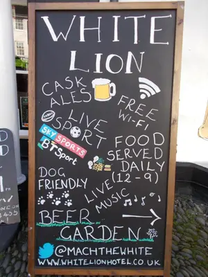 a chalkboard sign with writing on it with a cup of coffee at The White Lion Hotel in Machynlleth
