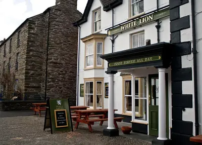 a white inn with picnic tables in front of it at The White Lion Hotel in Machynlleth