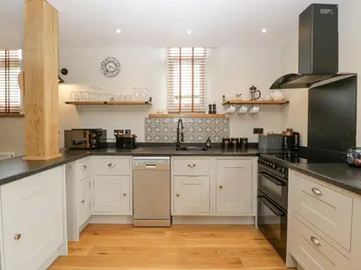a kitchen with white cabinets and black counter tops at The Old Chapel in Hereford