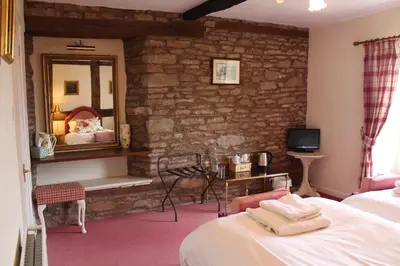a bedroom with a stone wall with a bed and a mirror at Rhydspence in Hay-on-Wye