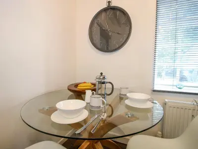 a glass table with bowls and a clock on the wall at Clematis Cottage in Shrewsbury