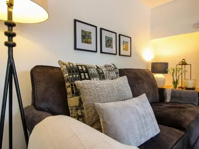 a living room with a brown couch with pillows at Clematis Cottage in Shrewsbury