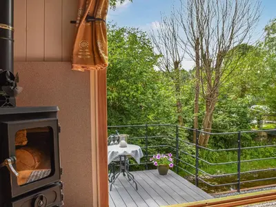 a balcony with a stove and a table on a deck at Bechan Brook Hut in Bettws Cedewain