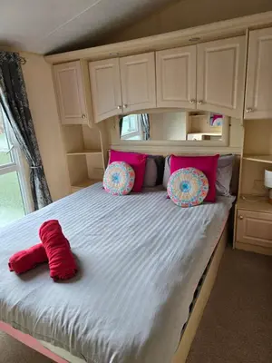 a bedroom with a bed with pink pillows on it at Wonderful 2 bedroom mobile home in Aberystwyth