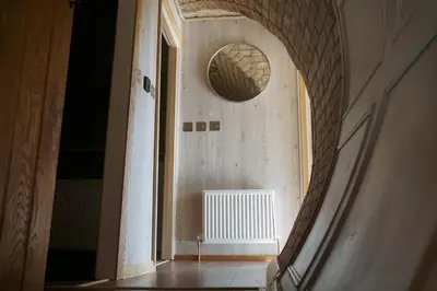 an arched hallway with a round mirror on the wall at Hares View in Rhayader