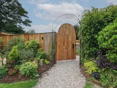 a wooden gate with an arch in a garden at Fioled in Welshpool