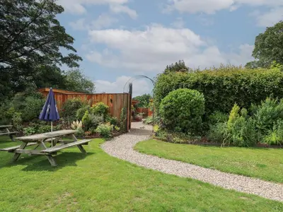 a picnic table and an umbrella in a garden at Rhosyn in Welshpool