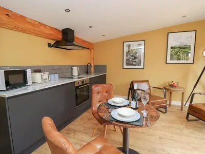 a kitchen and living room with a table and chairs at Rhosyn in Welshpool