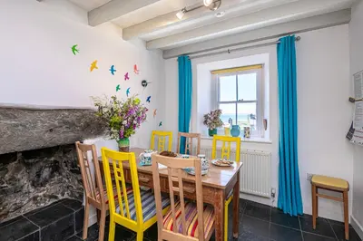 a dining room with a wooden table and yellow chairs at Stylish home from home with great views in Harlech