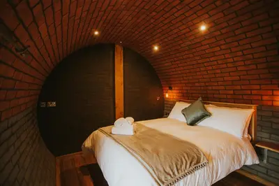 a bedroom with a bed in a brick wall at Otters View in Rhayader