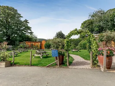 a picnic area with tables and benches in a park at Rhosyn - Uk40260 in Llangadfan