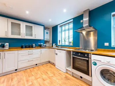 a kitchen with white cabinets and blue walls at Perfectly located 2 bed townhouse in Shrewsbury - Pass the Keys in Shrewsbury